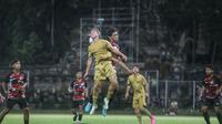 Pemain Barcelona Juvenil A melakukan duel udara dengan pemain Timnas U-17 dalam laga uji coba di Stadion Ngurah Rai Denpasar, Rabu (2/8/2023). (Bola.com/Alit Binawan)