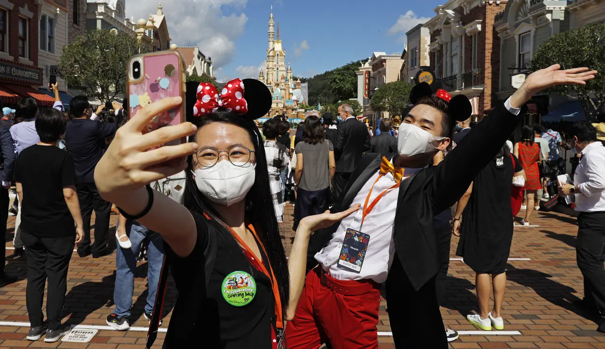 Para pengunjung yang mengenakan masker untuk mencegah penyebaran COVID-19 berswafoto di Disneyland Hong Kong, Kamis (18/6/2020). Disneyland Hong Kong kembali beroperasi pada 18 Juni 2020 dengan menerapkan sejumlah protokol kesehatan baru. (AP Photo/Kin Cheung)