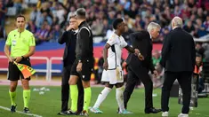 Pelatih Real Madrid, Carlo Ancelotti menarik tangan Vinicius Junior dan memaksanya untuk keluar dari lapangan saat pertandingan lanjutan Liga Spanyol 2023/2024 melawan Barcelona yang berlangsung di Estadi Olimpic Lluis Companys, Minggu (29/10/2023) dini hari WIB. (AFP/Josep Lago)