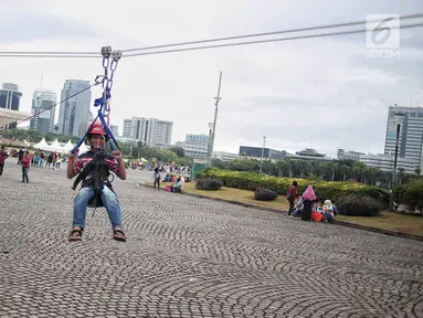 Seorang anak mencoba wahana flying fox di area Monas, Jakarta, Selasa (1/1). Wahana ini difasilitasi oleh Dinas Pemadam Kebakaran DKI Jakarta. (Liputan6.com/Faizal Fanani)