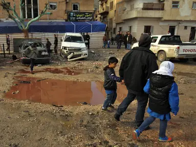 Warga berjalan melewati genangan darah dan air saat memeriksa ledakan di Kota Benghazi, Libya, Rabu (24/1). Juru bicara rumah sakit mengatakan jumlah korban tewas menyusul serangan bom mobil ganda ini meningkat menjadi 34 orang. (AFP PHOTO/Abdullah DOMA)