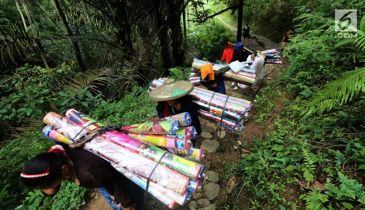 Masyarakat suku Baduy Luar berjalan kaki membawa bantuan berupa karpet untuk didistribusikan kepada korban kebakaran Kampung Cisaban II, Desa Kanekes, Banten, Kamis (01/6). Bantuan didistribusikan untuk 83 rumah. (Liputan6.com/Fery Pradolo)