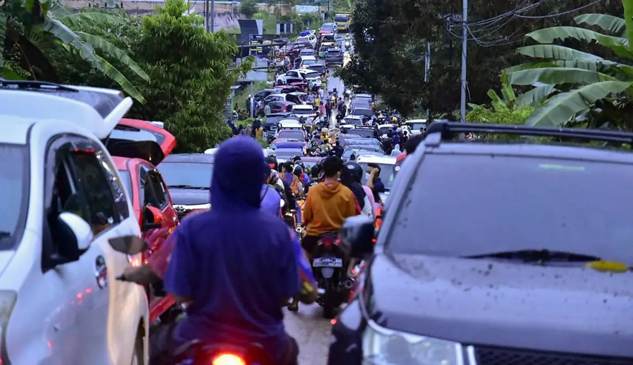 Warga memadati jalan saat mereka mencoba meninggalkan Mamuju usai diguncang gempa, Sulawesi Barat, Indonesia, Jumat (15/1/2021). Sejumlah rumah dan bangunan di Mamuju rusak akibat gempa magnitudo 6,2 yang berpusat di timur laut Majene. (Firdaus/AFP)
