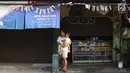 Warga menggendong bayinya di depan bengkel yang tutup usai kerusuhan di Mako Brimob Kelapa Dua, Depok, Jawa Barat, Rabu (9/5). Aparat kepolisian melakukan sterilisasi di kawasan tersebut lebih dari 100 meter. (Liputan6.com/Immanuel Antonius)