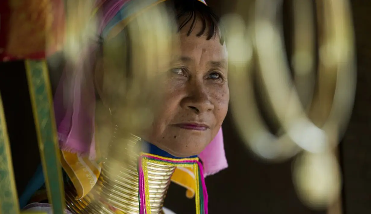 Seorang wanita etnis Kayan duduk di sebuah toko di desa PanPat, Kayan, Myanmar, Rabu (9/9/2015). Kaum perempuan Suku Kayan ini mengenakan banyak kalung berbentuk cincin di lehernya hingga membuat leher mereka panjang. (AFP PHOTO/Ye Aung THU)