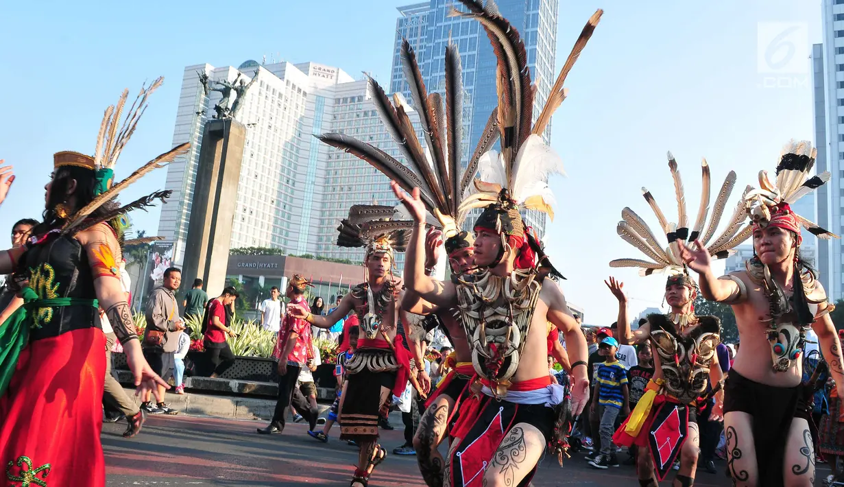 Sejumlah orang mengenakan pakaian adat menari saat pawai festival Budaya Borneo di Car Free Day, Jakarta, Minggu (30/7). Festival tersebut dalam rangka mengenalkan adat dan budaya borneo melalui pakaian dan musiknya. (Liputan6.com/Helmi Afandi)