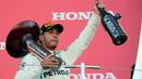 Pembalap Mercedes, Lewis Hamilton mengangkat trofi setelah memenangi Formula Satu (F1) Grand Pix Jepang di Sirkuit Suzuka, Jepang (7/10). Dengan kemenangan ini, Hamilton unggul 67 poin atas pesaing terdekatnya, Sebastian Vettel. (AP Photo/Ng Han Guan)