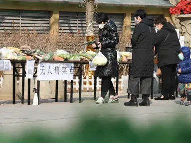 Warga membeli sayuran di kios sayur tak berpenjaga di permukiman di Distrik Xinhua, Shijiazhuang, Provinsi Hebei, China (12/2/2020). Kios sayur tak berpenjaga itu didirikan untuk menyediakan sayuran kepada warga dengan kontak minimal sebagai upaya melawan epidemi virus corona. (Xinhua/Xu Jianyuan)