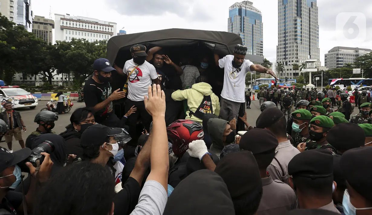 Polisi dan tentara menjaga masyarakat Papua yang memperingati Operasi Trikora 19 Desember 1961 di Patung Kuda, Jakarta, Sabtu (19/12/2020). Salah satu tuntutan massa adalah penghentian segala bentuk diskriminasi dan intimidasi terhadap mahasiswa Papua Barat. (Liputan6.com/Johan Tallo)