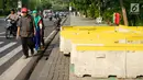 Pejalan kaki menghindari pembatas jalan yang menutupi trotoar di Jalan Medan Merdeka Utara, Jakarta, Rabu (3/7/2019). Pembatas jalan yang berada tidak pada tempatnya tersebut mengganggu pejalan kaki karena menutupi badan trotoar. (Liputan6.com/Immanuel Antonius)