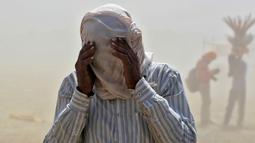 Seorang pria menutupi wajahnya dengan kain saat ia berjalan melintasi badai pasir di tepi sungai Gangga di Allahabad, India, Selasa (12/4/2016).  (REUTERS/Jitendra Prakash)