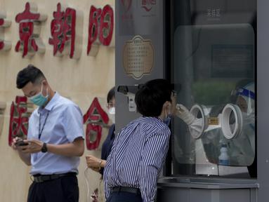 Seorang pekerja menjalani tes swab tenggorokan di fasilitas pengujian COVID-19 di Beijing, Senin (13/6/2022). Pejabat kesehatan kota mengatakan sejauh ini ada 166 kasus yang dikonfirmasi terkait dengan wabah yang dimulai di bar Heaven Supermarket di daerah Sanlitun pada Kamis, 9 Juni 2022. (AP Photo/Andy Wong)