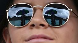  Refleksi pada kacamata seorang penonton saat pertandingan dihentikan karena hujan dalam turnamen tenis Wimbledon di All England Lawn Tennis Club, (1/7/2016). (AFP/Justin Tallis)