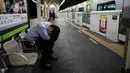 Seorang penumpang tertidur di peron saat kereta Yamanote Line melintas di Stasiun Shimbashi, Tokyo, Jepang, Sabtu (25/5/2019). (AP Photo/Jae C. Hong)