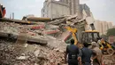 Petugas menggunakan alat berat mencari korban yang terjebak reruntuhan gedung ambruk di desa Shahberi, pinggiran New Delhi, India, Rabu (18/7). Setidaknya 100 orang dikerahkan untuk mengangkat reruntuhan. (AP Photo/Altaf Qadri)