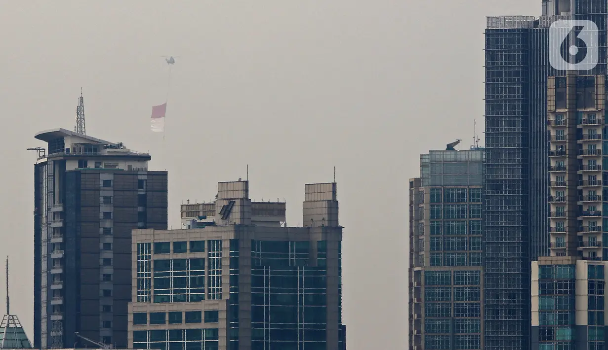 Bendera Merah Putih raksasa dikibarkan menggunakan helikopter TNI AU mengelilingi Jakarta, Jumat (13/8/2021). Pengibaran bendera yang dilakukan TNI AU sebagai bentuk latihan untuk persiapan puncak peringatan HUT ke-76 RI pada tanggal 17 Agustus 2021 mendatang. (Liputan6.com/Herman Zakharia)