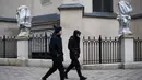 Pejalan kaki berjalan melewati patung-patung yang dibungkus dengan plastik di Katedral Latin di Lviv, 5 Maret 2022. Warga kota Lviv membungkus semua patung yang ada di kota tersebut untuk melindungi warisan sejarahnya dari kerusakan akibat serangan di tengah konflik Rusia-Ukraina. (Daniel LEAL/AFP)