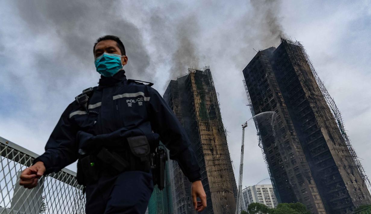Merujuk data sensus pemerintah tahun 2021, dengan 1.984 apartemen ada sekitar 4.600 penduduk tinggal di sana. Tampak dalam foto, seorang petugas polisi berjalan melewati lokasi kebakaran di Wang Fuk Court, sebuah kompleks perumahan di distrik Tai Po, Wilayah Baru Hong Kong, Kamis 27 November 2025. (AP Photo/Chan Long Hei)