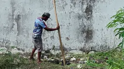 Seorang pria memasukkan kayu ke dalam lubang yang digunakan narapidana untuk kabur dari Lapas Kerobokan, Bali, Senin (19/6). Empat narapidana asing kabur melalui lubang sepanjang 15 m yang mengarah ke parit di luar bangunan Lapas. (AP /Firdia Lisnawati)