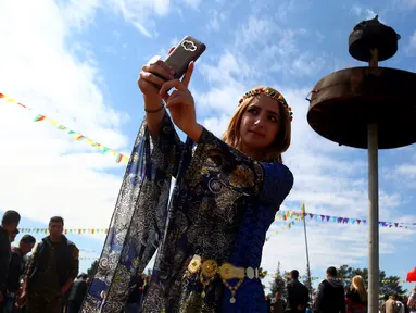 Seorang wanita Kurdi Suriah berselfie selama Perayaan Newroz di Kota Qamishli, Suriah (21/3). Newroz, juga dikenal sebagai Nawroz atau Nowruz adalah sebuah Festival Tahun Baru Persia Kuno. (AFP Photo / Delil Souleiman)