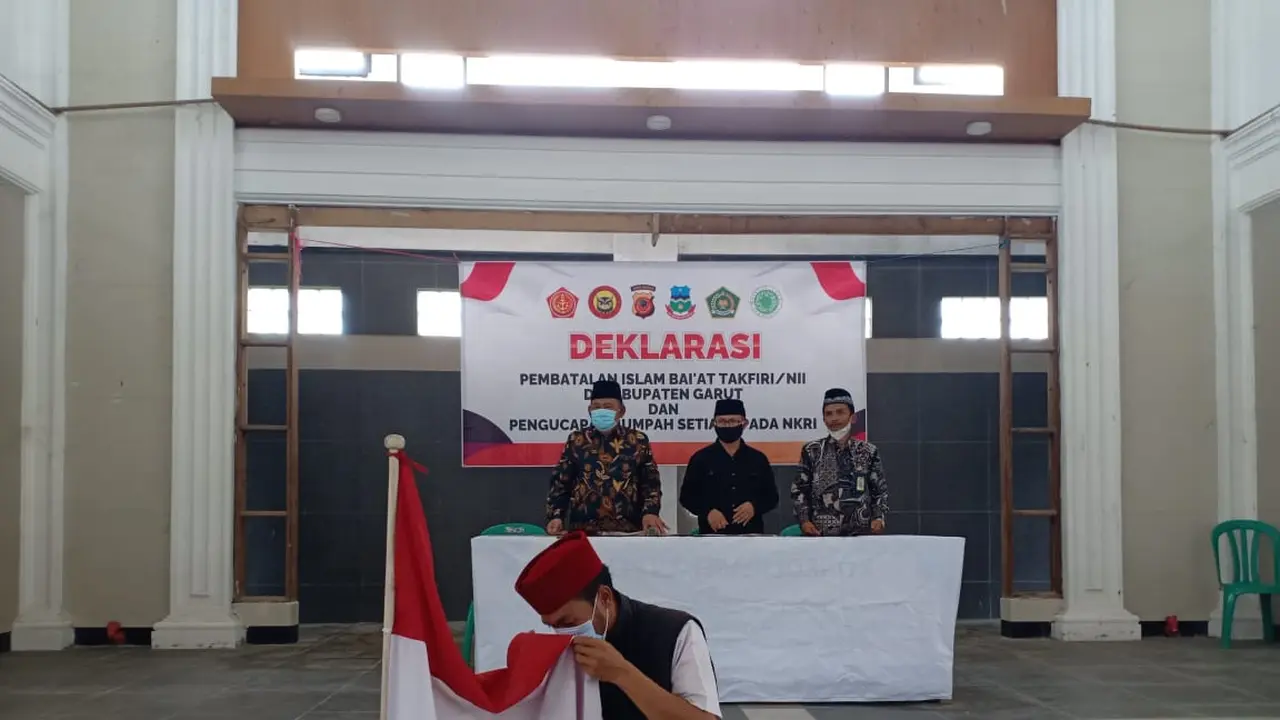 Salah seorang warga bekas anggota NII tengah mencium bendera merah putih sebagai bukti ikrar kembali kepada pangkusan NKRI. (Liputan6.com/Jayadi Supriadin)