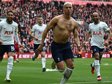 Pemain Tottenham Hotspur, Richarlison melakukan selebrasi dengan melepas jersey setelah mencetak gol penyeimbang ke gawang Liverpool di tambahan waktu babak kedua dalam pertandingan lanjutan English Premier League 2022/2023 yang berlangsung di Anfield stadium, Minggu (30/4/2023). (AFP/Paul Ellis)