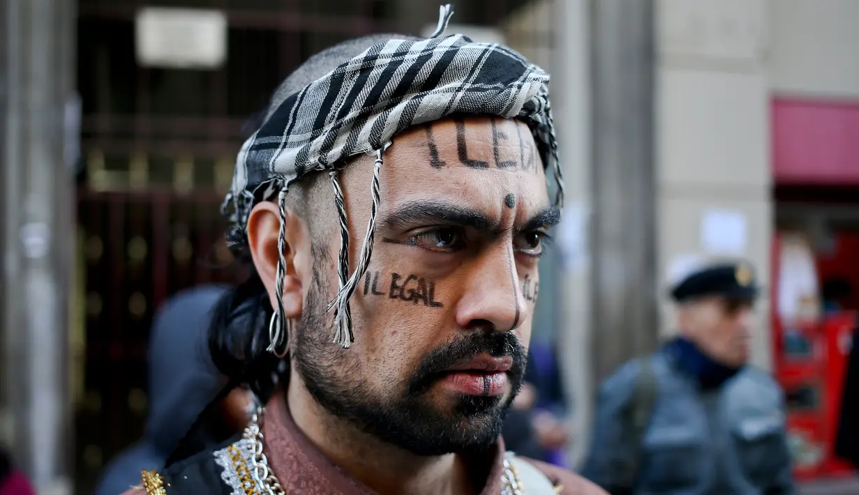 Seorang penari dengan tulisan ‘Ilegal’ di wajahnya melakukan demonstrasi di pusat kota Santiago, Chili, Minggu (20/8). Migran Amerika Latin di Chili berkumpul melakukan aksi protes terhadap beberapa calon presiden dari sayap kanan. (Esteban Felix/AP)