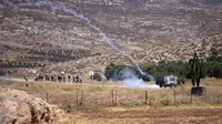 Tentara Israel menembakkan gas air mata untuk membubarkan pengunjuk rasa Palestina saat membakar ban dan memblokir jalan yang melewati Desa Mughayer, Tepi Barat, utara Ramallah, 29 Juli 2022. Warga Palestina yang memprotes aktivitas permukiman Israel memblokir jalan utama dan bentrok dengan pemukim Israel, sementara tentara menembakkan gas air mata untuk membubarkan mereka. (AP Photo/Nasser Nasser)