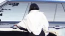 Kylie Jenner terlihat memakai atasan cropped berwarna hitam, celana pendek, jaket oversized berwarna putih dan tas yang melingkar di pinggangnya. (SplashNews/TMZ)