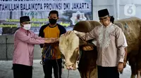 Gubernur DKI Jakarta Anies Baswedan (kanan) menyerahkan sapi kurban di Balai Kota, Jakarta, Jumat (31/7/2020). Pada Hari Raya Idul Adha tahun ini, Anies menyumbangkan sapi kurban jenis limosin seberat 1,3 ton. (Liputan6.com/Immanuel Antonius)