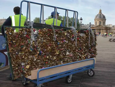 Para pekerja memindahkan sebuah pagar besi yang dipenuhi gembok cinta di Jembatan Pont des Arts di atas Sungai Seine, Paris, Perancis, Senin (1/6/2015). (REUTERS/Philippe Wojazer)