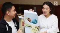 Ayu Dewi dan suami memperlihatkan foto anak kedua mereka saat jumpa pers di Rumah Sakit kawasan Pondok Indah, Jakarta, Senin (10/7). Ayu Dewi berharap anaknya nanti memiliki akhlak yang indah seperti Nabi Muhammad SAW. (Liputan6.com/Herman Zakharia)