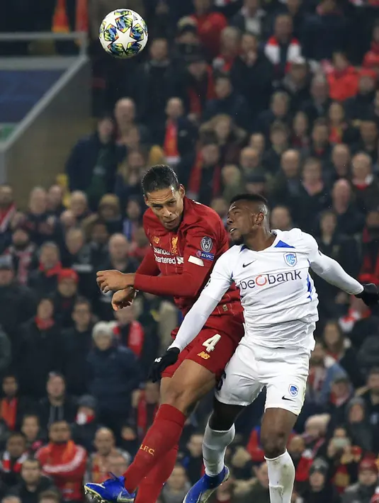 Bek Liverpool, Virgil van Dijk berebut bola udara dengan bek KRC Genk, Carlos Cuesta pada pertandingan lanjutan Grup E Liga Champions di Stadion Anfield, Inggris (5/11/2019). Liverpool menang tipis 2-1 atas Genk. (AP Photo/Jon Super)