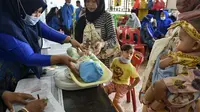 Seorang balita ditimbang badannya sebelum menerima vaksin campak dan polio di sebuah posyandu di Banda Aceh, Aceh, Rabu (4/10/2020). Pemberian vaksin polio dan vaksin campak secara gratis yang berlanjut di tengah pandemi COVID-19 bertujuan memperkuat imunitas anak. (CHAIDEER MAHYUDDIN / AFP)