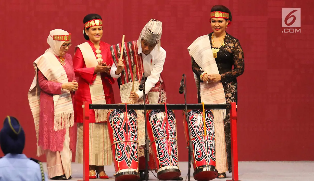 Presiden Joko Widodo memukul alat musik tradisional Batak disaksikan Ibu Negara Iriana Joko Widodo, beserta Ibu Mufida Jusuf Kalla saat membuka pameran Kriyanusa Dewan Kerajinan Nasional 2017, di JCC, Jakarta, Rabu (27/9). (Liputan6.com/Angga Yuniar)