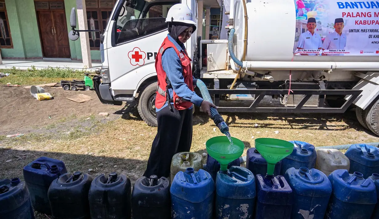 Relawan Palang Merah Indonesia (PMI) Kabupaten Bangkalan mengisi air bersih ke dalam jeriken milik warga di Dusun Batangan Tengah, Desa Batangan, Kecamatan Tanah Merah, Kabupaten Bangkalan, Jawa Timur, Selasa (21/7/2026). (AFP/ Juni Kriswanto)
