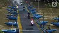 Pengendara sepeda motor melintasi jembatan perahu di atas Sungai Citarum, Karawang, Jawa Barat, Sabtu (20/11/2021). Jembatan perahu ini menjadi jalan alternatif yang menghubungkan antara Desa Anggadita dengan Kawasan Pabrik Dusun Rumambe 1. (merdeka.com/Imam Buhori)