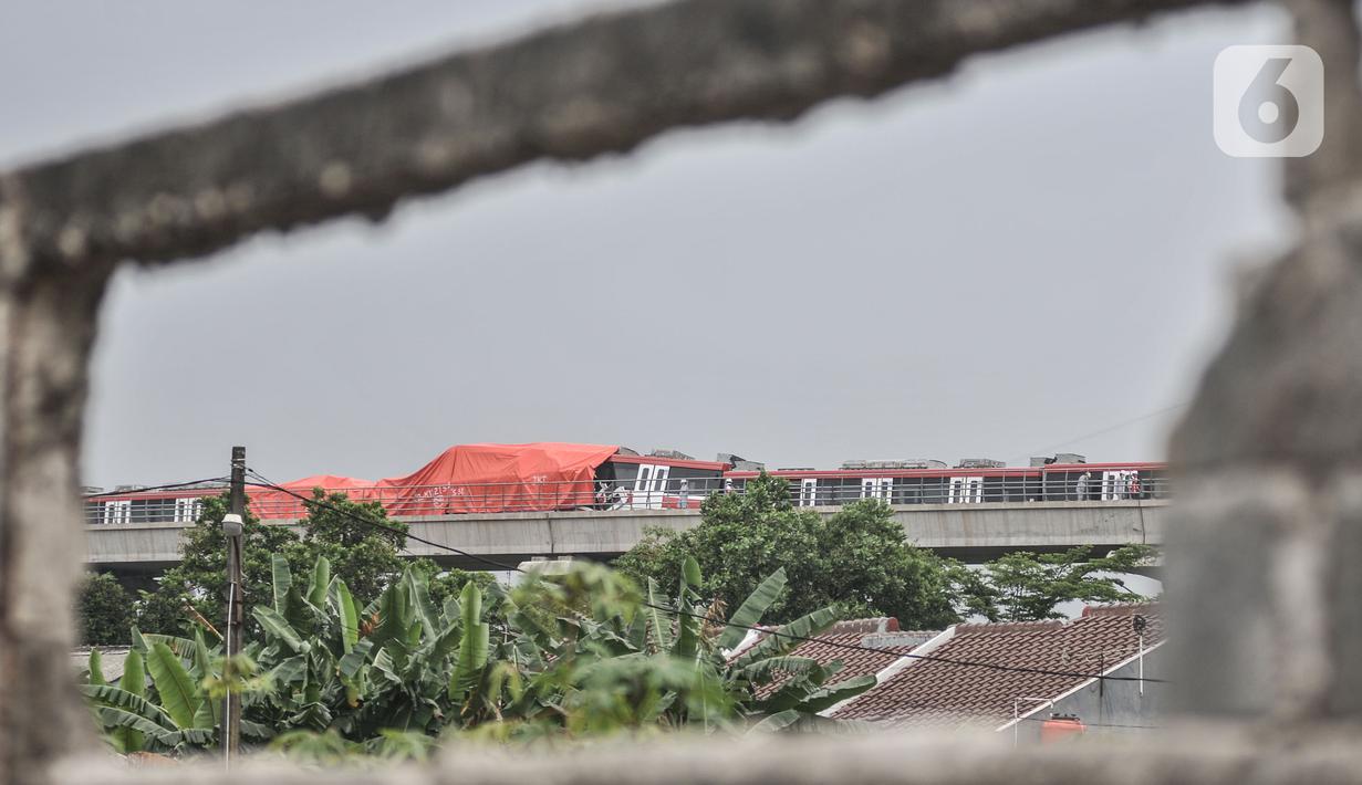 Petugas menggunakan terpal oranye untuk menutupi kereta LRT Jabodebek usai kecelakaan di kawasan Munjul, Cibubur, Jakarta, Senin (25/10/2021). Belum diketahui penyebab tabrakan tersebut dan hingga kini petugas masih menjaga di area kecelakaan. (merdeka.com/Iqbal S Nugroho)
