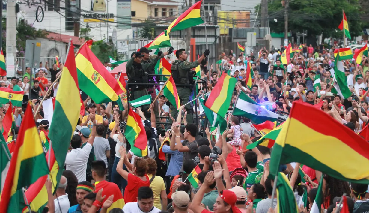 Orang-orang mengibarkan bendera Bolivia merayakan pengunduran diri Presiden Evo Morales di La Paz, Minggu (10/11/2019). Morales memutuskan mengundurkan diri buntut aksi protes yang dilatarbelakangi dugaan dirinya melakukan kecurangan dalam pemilu dalam beberapa pekan terakhir. (JORGE BERNAL/AFP)