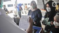 Petugas memeriksa kelengkapan syarat penumpang kereta api jarak jauh sebelum memasuki peron di Stasiun Pasar Senen, Jakarta Pusat, Minggu (17/7/2022). PT KAI mulai hari ini kembali memberlakukan syarat wajib bagi penumpang kereta jarak jauh, antara lain tes PCR bagi yang baru vaksin pertama dan tes antigen untuk vaksin kedua sebagai langkah mencegah penyebaran Covid-19. (merdeka.com/Iqbal S Nugroho)