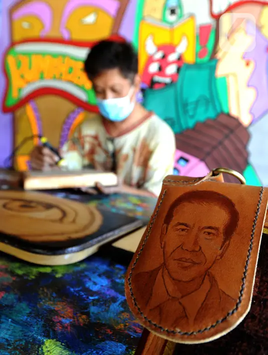 Arfan (55) menyelesaikan karya seni lukis bakar di galeri Rumah Oenik, Kampung Ragamukti, Tajur Halang, Bogor, Senin (28/9/2020). Arfan menjual karya seni lukis bakarnya dengan harga 300 ribu sampai jutaan rupiah dilihat dari besar dan tingkat kerumitannya. (merdeka.com/Arie Basuki)