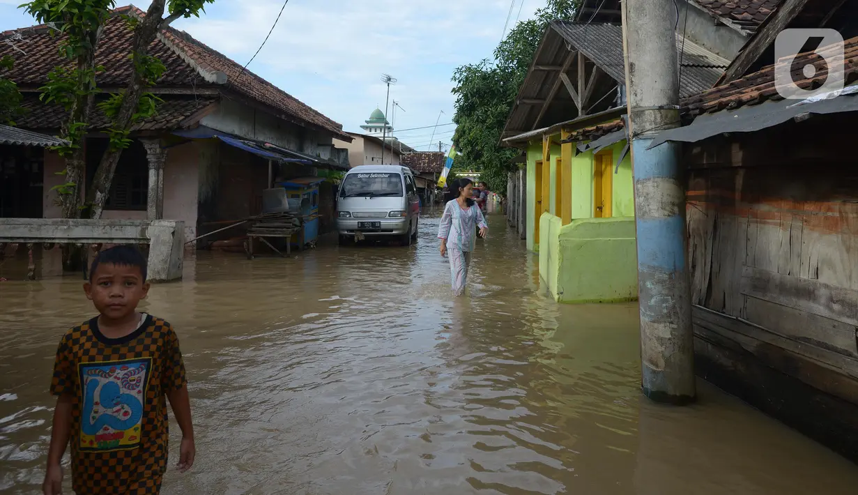 Anak-anak dan warga beraktivitas saat banjir di Desa Sukajaya, Serang, Banten, Rabu (2/3/2022). Banjir yang melanda kawasan Masjid Banten Lama setelah curah hujan tinggi mengguyur Kota Serang beberapa hari lalu mengakibatkan Kali Cibanten meluap dan menggenangi 22 titik. (merdeka.com/Imam Buhori)