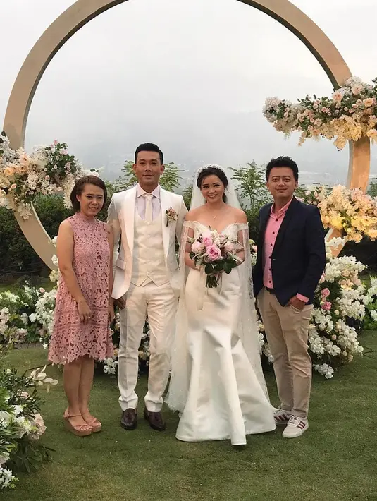Denny tampak gagah mengenakan setelan jas berwarna putih, senada dengan Olivia yang juga bergaun putih. Sang mempelai perempuan makin cantik dengan ornament bunga-bunga yang juga dominan putih. (FOTO: Instagram)