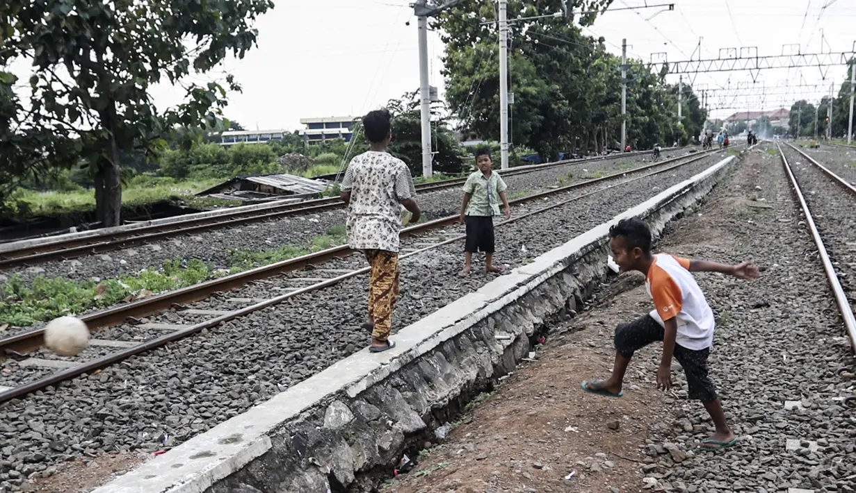Anak-anak bermain bola di tengah perlintasan kereta api kawasan Ancol, Jakarta Utara, Kamis (19/5/2022). Kelompok umur kasus diduga hepatitis akut terbanyak adalah di bawah 5 tahun ada tujuh kasus, 6 sampai 10 tahun ada dua kasus, dan 11-16 tahun ada lima kasus. (Liputan6.com/Johan Tallo)