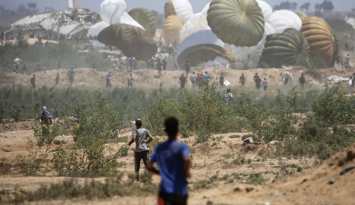 Warga Palestina bergegas menuju lokasi pendaratan paket bantuan yang diterjunkan di wilayah Nuseirat, Jalur Gaza tengah, saat penerjunan bantuan dari udara di atas wilayah Palestina yang dikepung Israel pada 6 Agustus 2025. (Eyad BABA/AFP)
