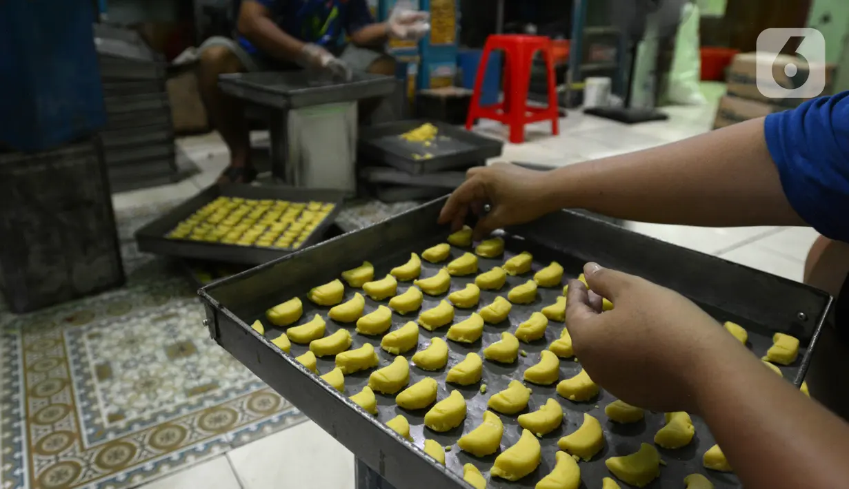 Pekerja menata adonan kue kering untuk dipanggang dalam oven di usaha pembuatan kue Pusaka Kwitang di kawasan Kwitang, Jakarta Pusat, Selasa (27/4/2021). Kue kering yang diproduksi antara lain putri salju, kastengel, nastar, kue lidah kucing, dan kue kacang. (merdeka.com/Imam Buhori)
