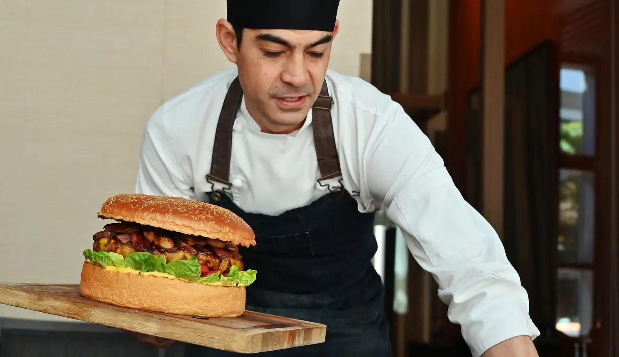 Chef dari restoran The Oak Door, Patrick Shimada berpose dengan burger raksasa di hotel Grand Hyatt Tokyo, Senin (1/4). Hamburger berisi hamparan daging wagyu yang dipotong kecil-kecil berbobot 3 kilogram itu dijual dengan harga fantastis, yaitu $900 atau setara Rp 12,8 juta. (CHARLY TRIBALLEAU/AFP)