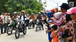 Warga menyambut kedatangan Presiden Joko Widodo saat mengendarai motor trail di Muara Gembong, Bekasi (1/11).  Jokowi mengenakan kemeja putih, celana jeans, dengan balutan jaket rompi berwarna hitam. (Liputan6.com/Biro Pers Kepresidenan/Agus Suparto)