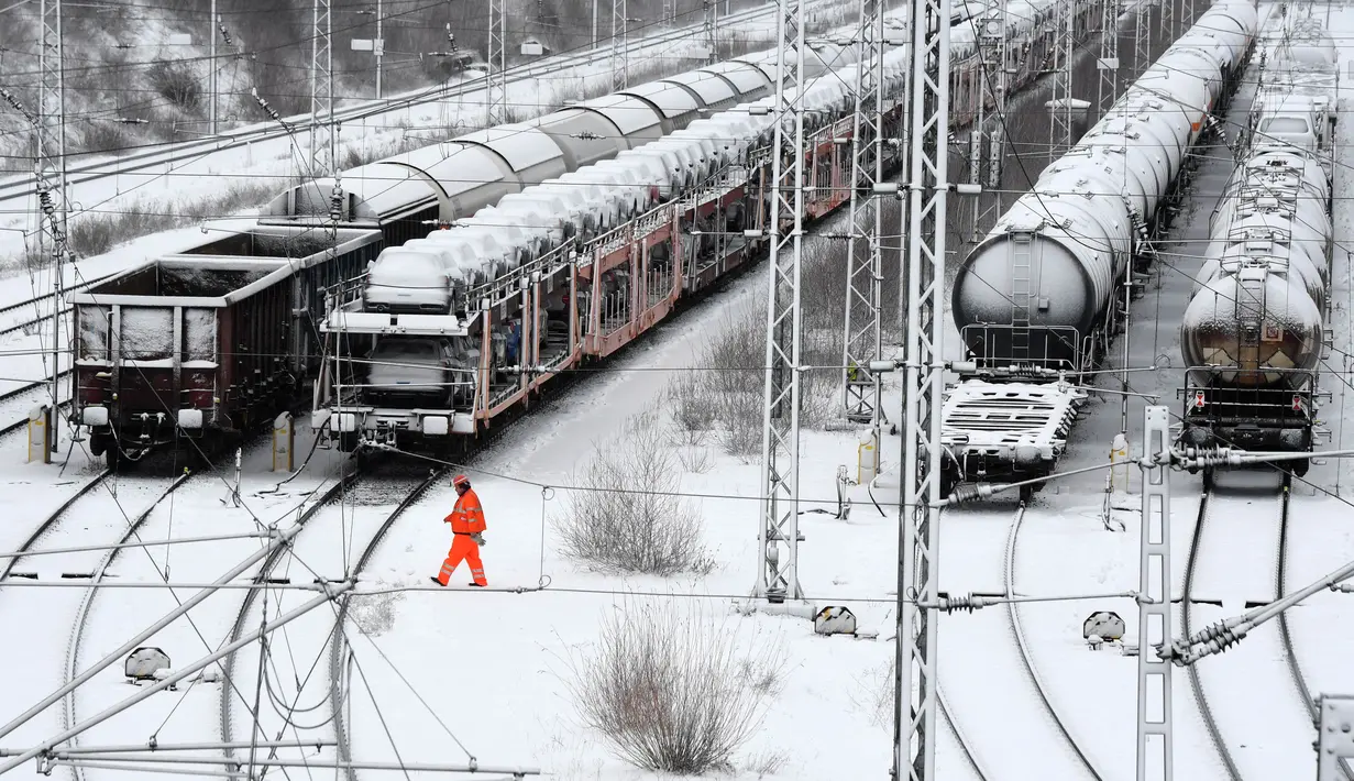 Seorang karyawan berjalan di terminal kereta barang saat salju lebat turun di Munich, Jerman, Rabu (9/1). Salju lebat menyelimuti kota-kota di Jerman. (Christof STACHE/AFP)