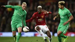 Gelandang Manchester United, Paul Pogba (tengah) berebut bola dengan gelandang Jordan Veretout dan bek Kevin Malcuit pada laga Liga Eropa di Olad Trafford, Inggris, (16/2). MU menang telak atas Saint-Etienne 3-0. (AFP Photo / Oli Scarff)